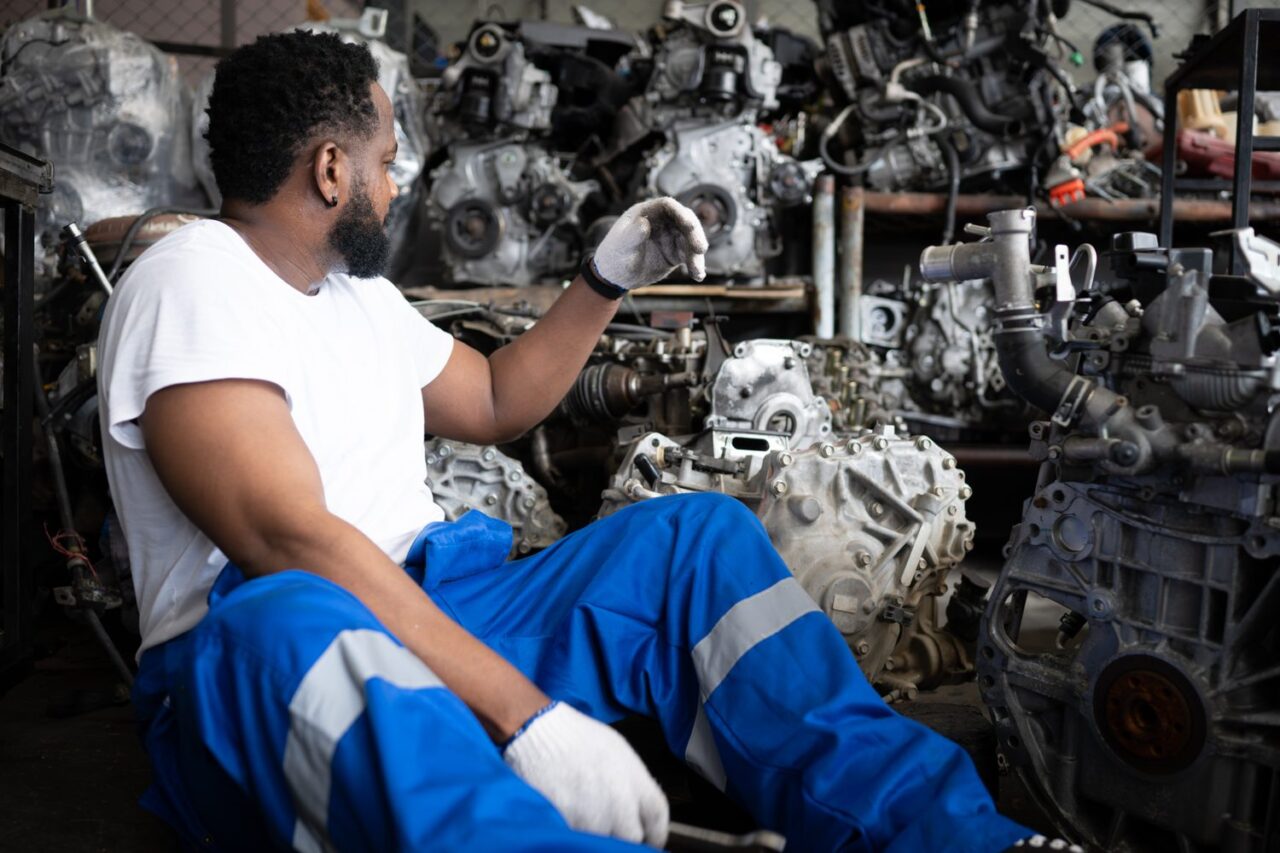 Mécanicien inspectant le moteur diesel d’une voiture d’occasion pour évaluer sa fiabilité.