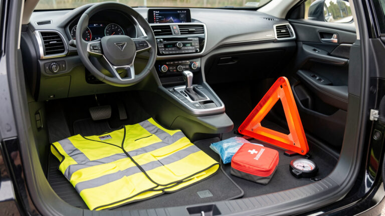 Vue réaliste d’une voiture moderne avec des équipements de sécurité obligatoires disposés dans le coffre et sur le sol, éclairage naturel et détails nets.